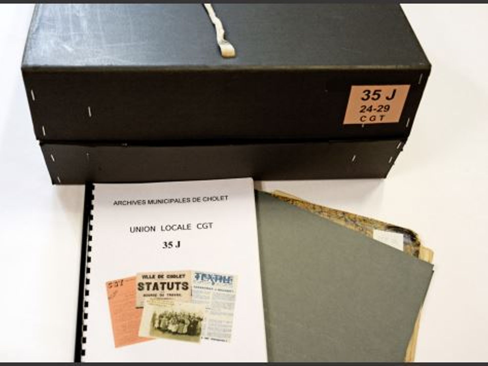 Photographie d'une boîte d'archives, avec des dossiers et l'inventaire correspondant